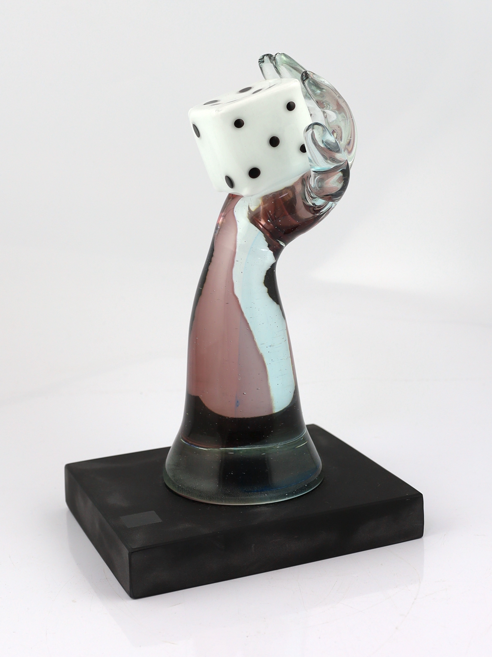 A Murano Vetreria amethyst glass arm, holding a white, black spotted, dice in hand